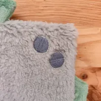 Détail broderie du doudou original Tibo le Robot. Un doudou sensoriel ultra-doux conçu pour apaiser bébé grâce à l’odeur de Maman et ses coussinets parfumés.