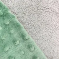 Zoom sur les textures ultra-douces du doudou Tibo le Robot : teddy moelleux et minky à pois. Un doudou sensoriel idéal pour apaiser bébé avec l’odeur des parents.