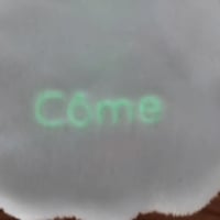 Gros plan sur le prénom au dos du petit doudou Côme le Fantôme qui brille dans le noir - Atelier Bombus