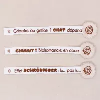Les trois modèles de marque-pages Patsy brodés sur ruban blanc, posés à plat